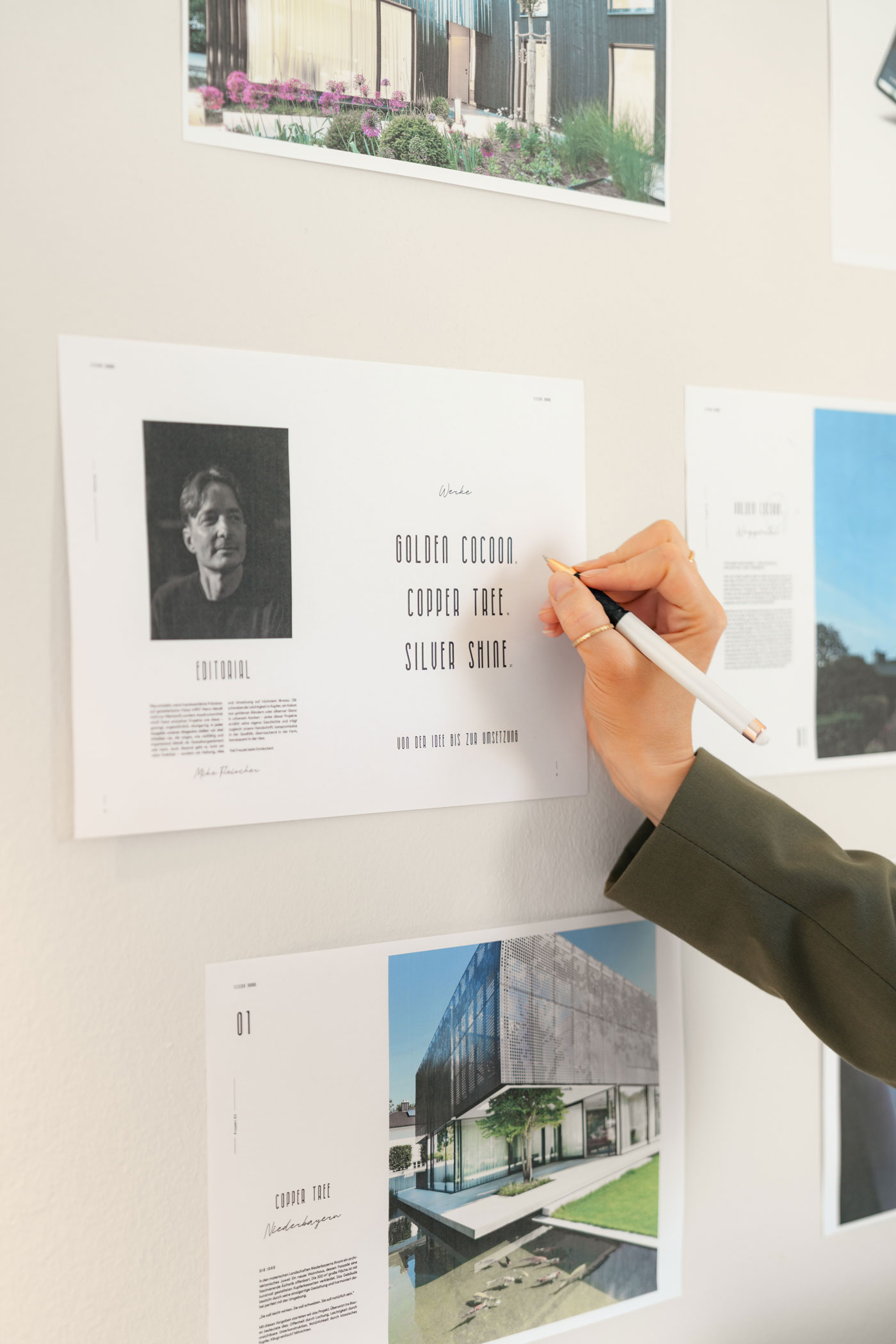 Hand schreibt auf Branding-Konzept an einer Wand mit Design-Layouts