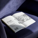 Aufgeschlagene Unternehmensbroschüre „Fleischer Journal“ mit Architekturzeichnung auf einem Sessel