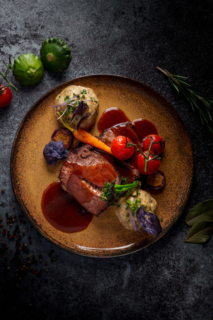 Rinderbraten mit Sauce, Gemüse und Knödel auf einem Teller angerichtet