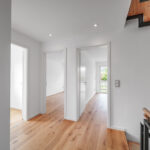 Heller Flur im Obergeschoss einer Doppelhaushälfte in Aystetten bei Augsburg mit Holzparkett und moderner Treppe